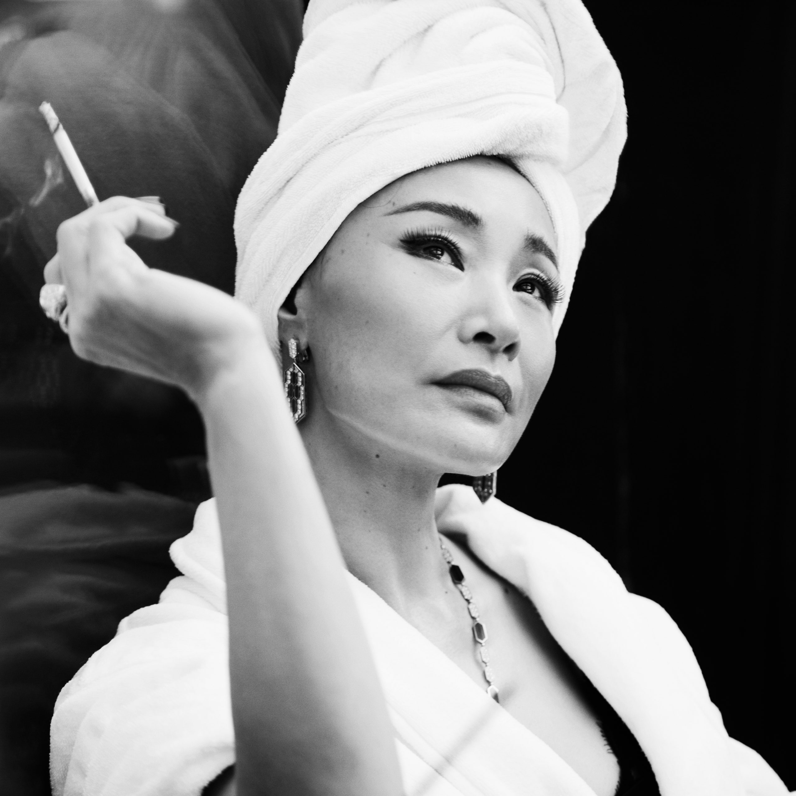 Image may contain Joan Chen Face Head Person Photography Portrait Body Part Finger Hand Adult and Smoke